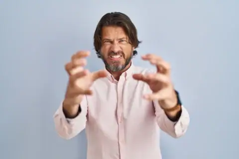 knappe man van middelbare leeftijd met een elegante shirtachtergrond die gefrustreerd schreeuwt van woedehanden die boos proberen te wurgen